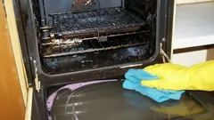 Oven schoonmaken met gele handschoenen en blauwe doek