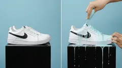Witte sneaker Nike wordt waterafstotend gemaakt met spray tegen een blauwe achtergrond.